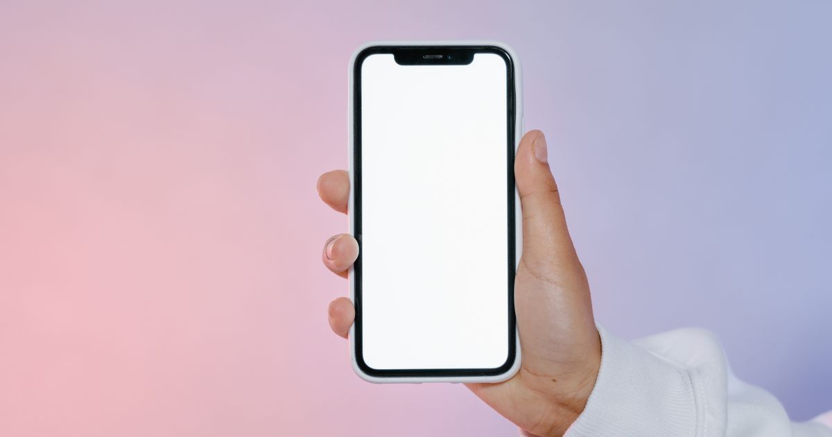 Mano sosteniendo un celular con la pantalla en blanco, listo para mostrar un documento