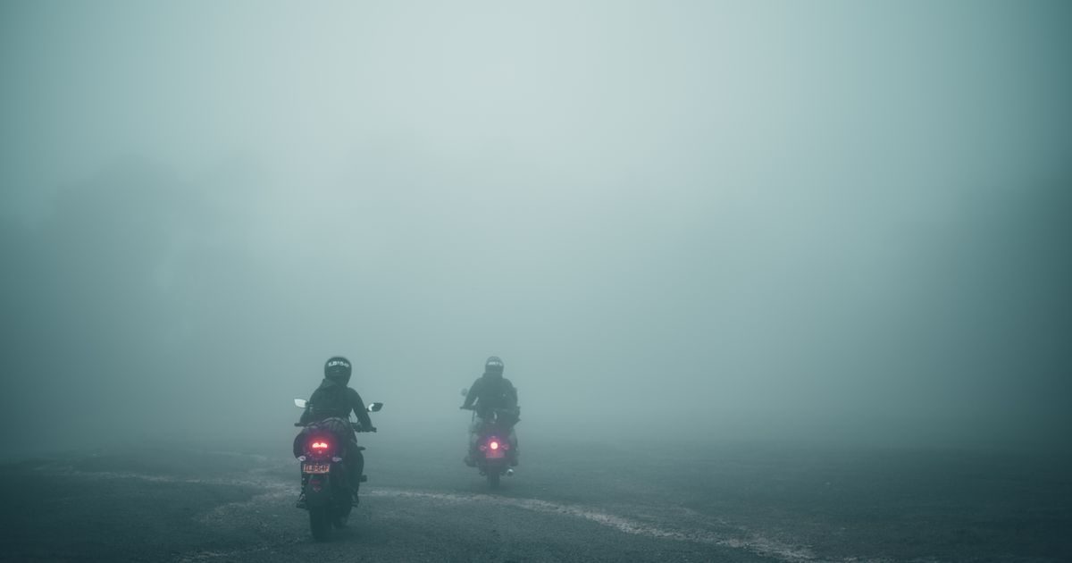 Dos motociclistas circulando entre la niebla en una vía de Soacha, Colombia