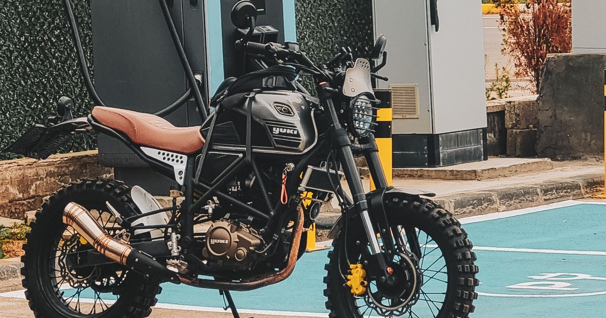 Motocicleta eléctrica estacionada junto a un punto de carga en la calle