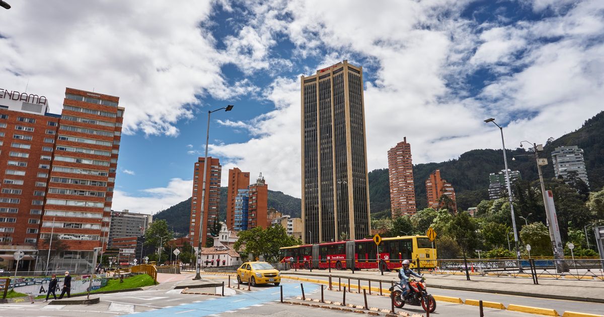 Calle de Bogotá con TransMilenio, taxi y motociclista en tráfico