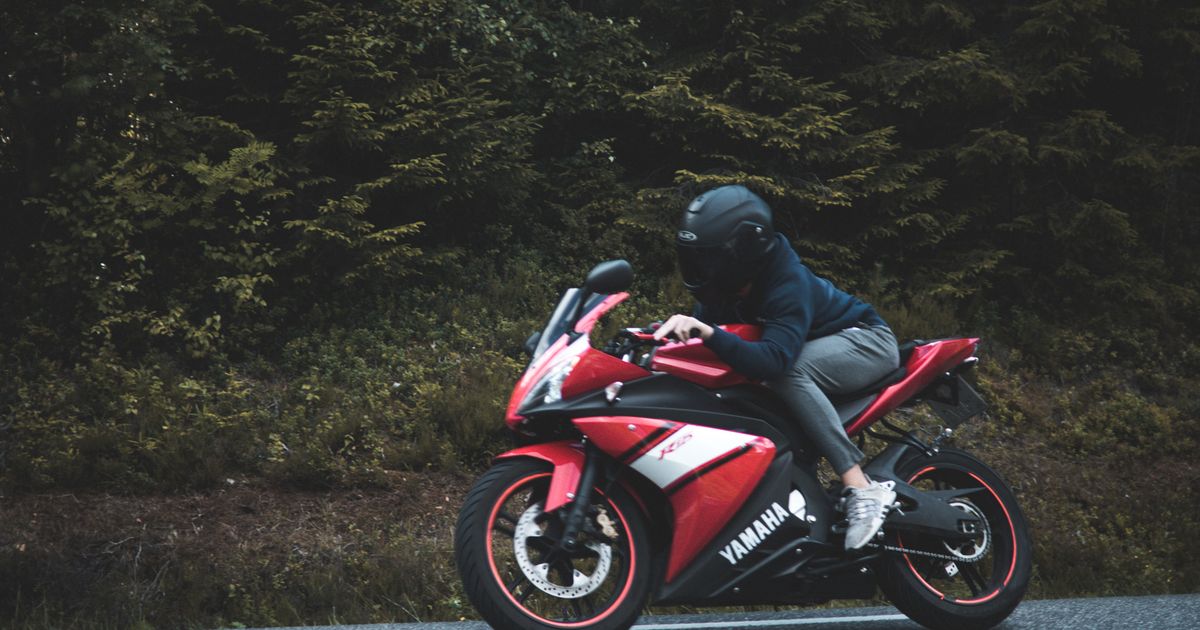 Motociclista sobre una moto deportiva Yamaha de carenado rojo y negro en carretera